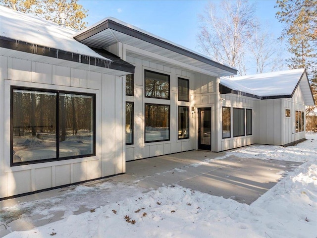 snow covered rear of property with board and batten siding