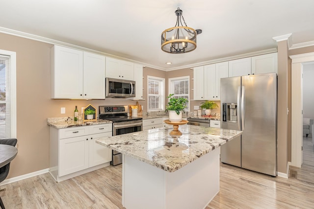 kitchen featuring white cabinets, appliances with stainless steel finishes, a center island, and ornamental molding