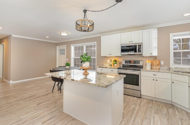 kitchen featuring light wood-type flooring, appliances with stainless steel finishes, white cabinetry, and crown molding