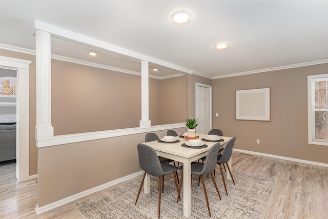 dining room with baseboards, plenty of natural light, decorative columns, ornamental molding, and light wood-style floors