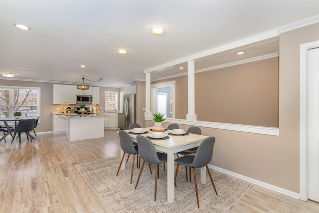 dining room with light wood finished floors, a healthy amount of sunlight, and crown molding