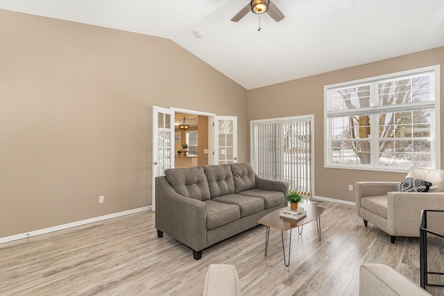 living area featuring vaulted ceiling, baseboards, and light wood-type flooring