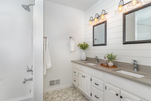 bathroom with a sink, visible vents, double vanity, and shower / bathing tub combination