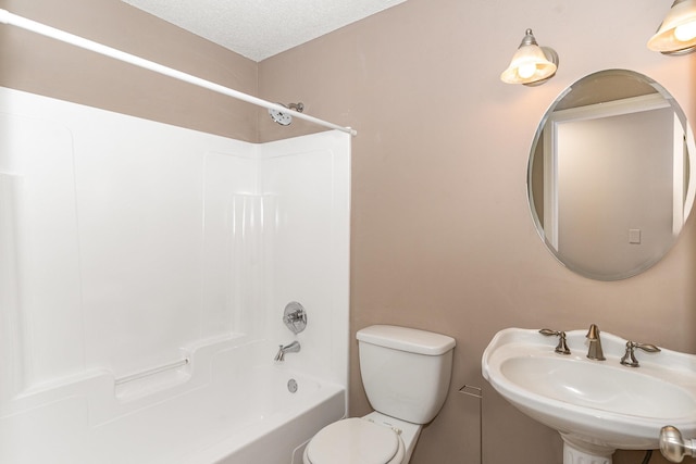 bathroom featuring a textured ceiling, toilet, tub / shower combination, and a sink