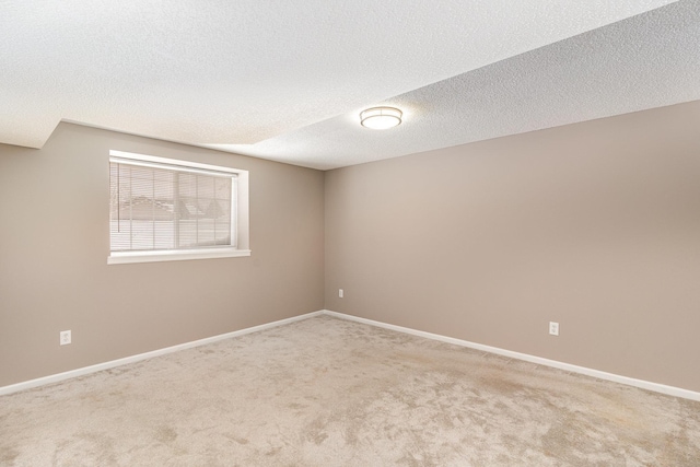 spare room featuring carpet, baseboards, and a textured ceiling