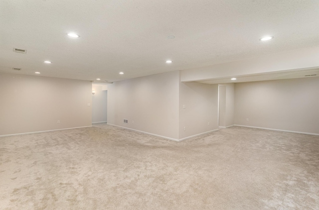 finished basement with light carpet, visible vents, and recessed lighting