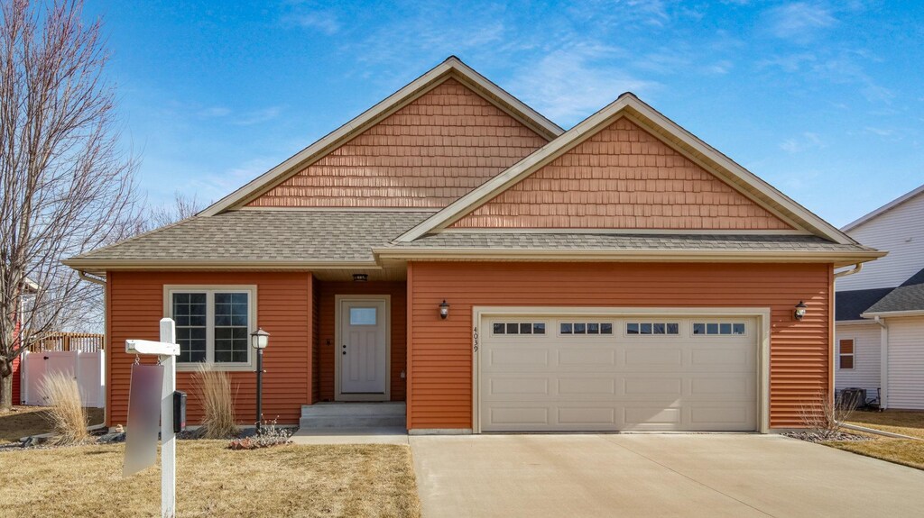 view of front of house featuring concrete driveway, an attached garage, and a shingled roof