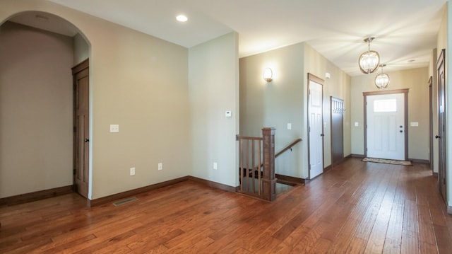 entrance foyer featuring baseboards, arched walkways, and hardwood / wood-style floors