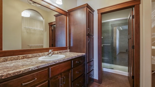 bathroom with tile patterned floors, a spacious closet, a stall shower, and vanity