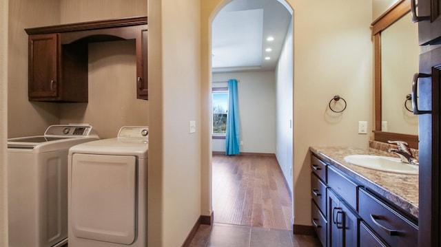 clothes washing area featuring baseboards, laundry area, arched walkways, a sink, and washing machine and dryer