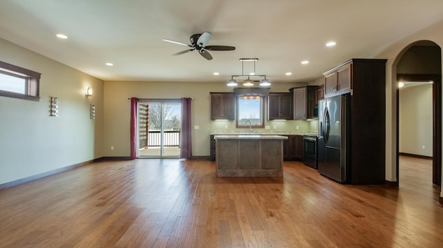 kitchen with fridge with ice dispenser, wood finished floors, electric range oven, arched walkways, and light countertops