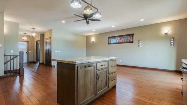 kitchen featuring a kitchen island, baseboards, light countertops, recessed lighting, and dark wood-style floors