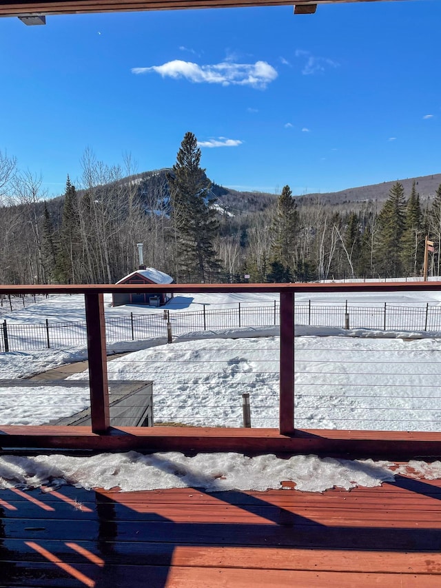 yard covered in snow featuring a deck and a wooded view