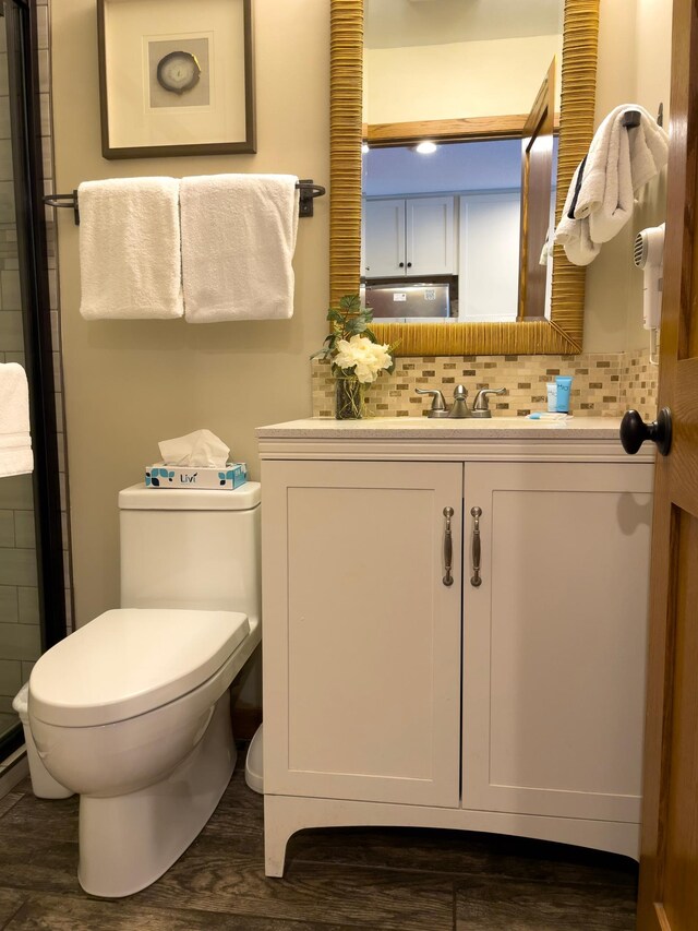 bathroom featuring vanity, toilet, wood finished floors, and backsplash