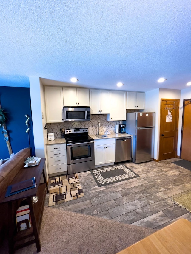 kitchen featuring a sink, stainless steel appliances, light countertops, white cabinets, and tasteful backsplash