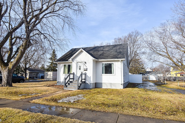 view of front of property with roof with shingles, a front yard, and fence