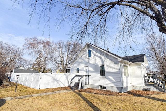 view of side of home featuring a lawn and fence