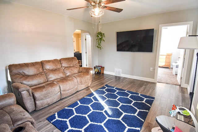 living area with arched walkways, visible vents, ceiling fan, and wood finished floors