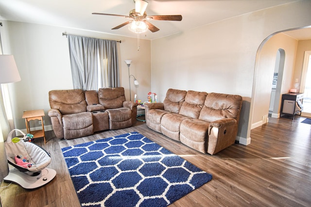 living room with arched walkways, baseboards, a ceiling fan, and wood finished floors