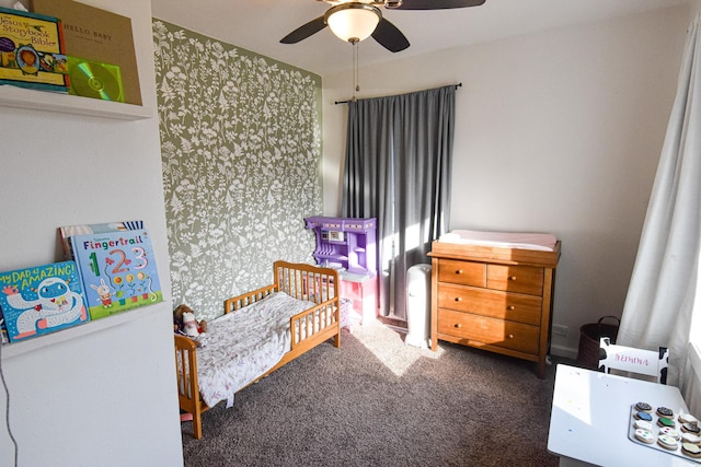 bedroom featuring a crib, a ceiling fan, carpet floors, and wallpapered walls