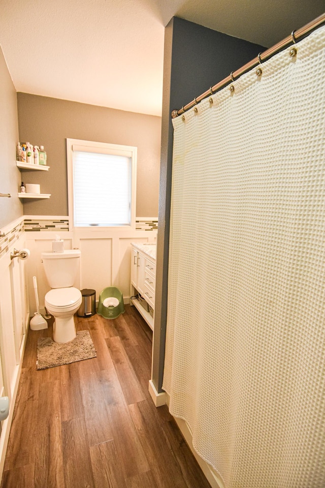 full bathroom with toilet, wood finished floors, and wainscoting