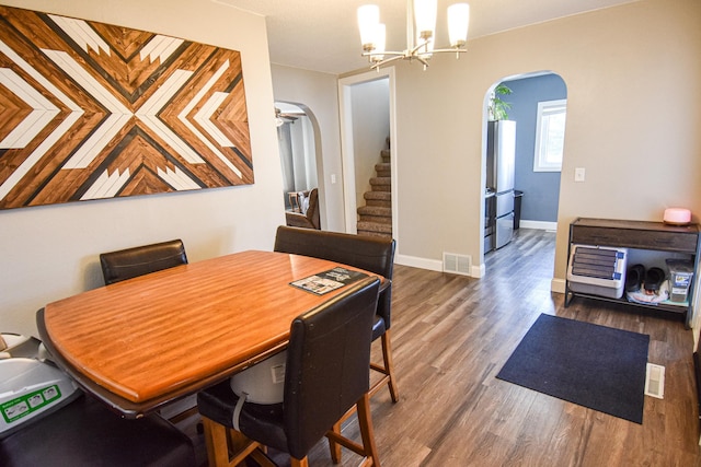 dining space with stairway, wood finished floors, visible vents, arched walkways, and a notable chandelier