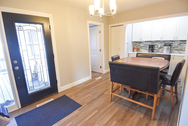 dining area with visible vents, light wood-style flooring, baseboards, and an inviting chandelier