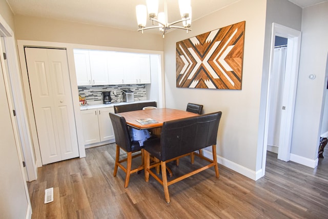 dining area with a notable chandelier, baseboards, visible vents, and wood finished floors