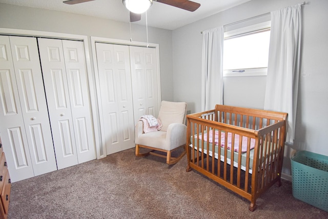 carpeted bedroom with multiple closets, a nursery area, and ceiling fan