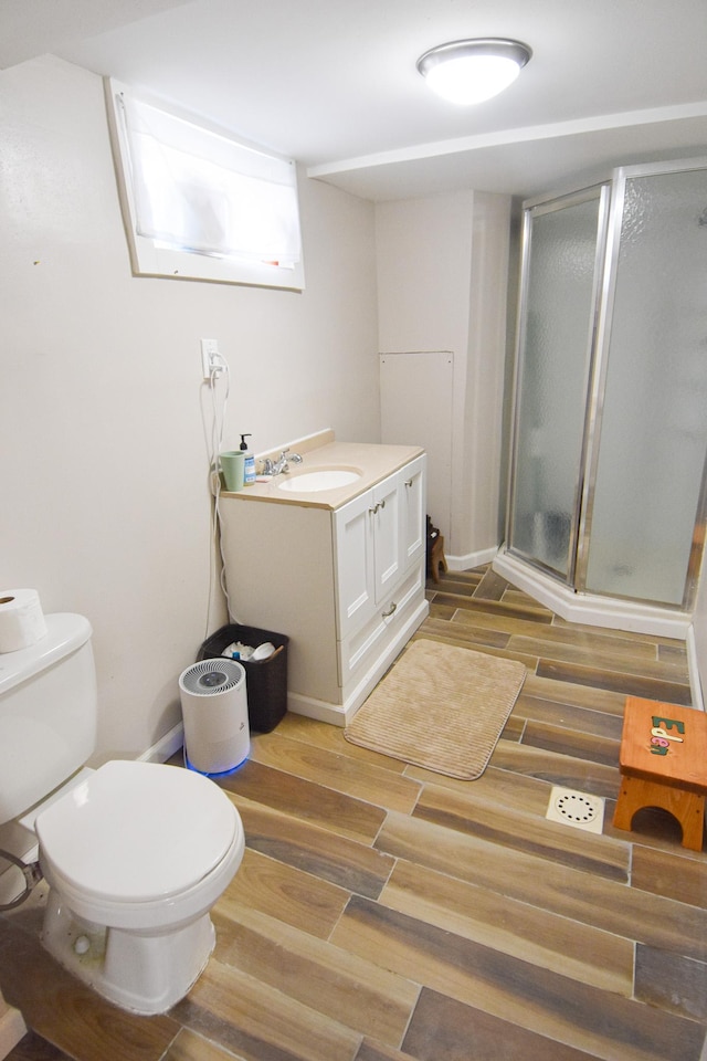 bathroom featuring vanity, toilet, a shower stall, and wood tiled floor