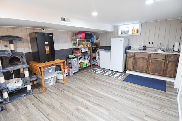 kitchen with light countertops, visible vents, freestanding refrigerator, and light wood-type flooring