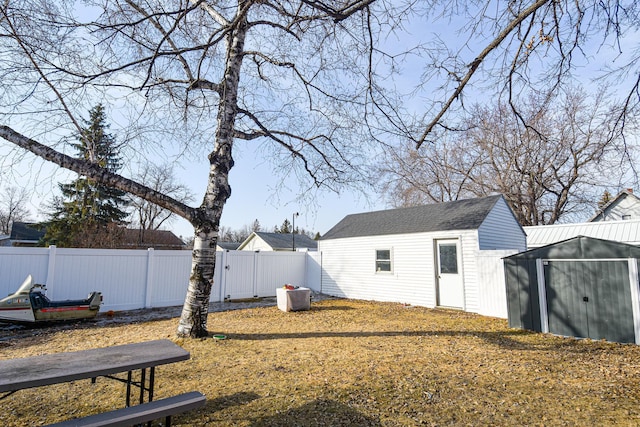 view of yard with an outbuilding, a fenced backyard, and a shed