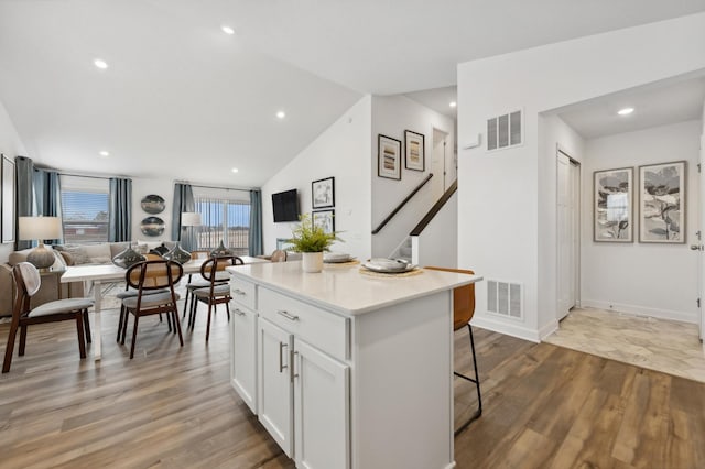 kitchen featuring a breakfast bar, visible vents, a kitchen island, and white cabinetry