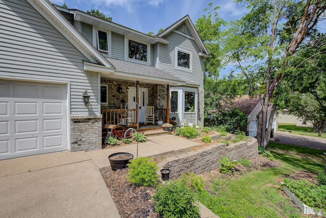 traditional-style home featuring a garage, brick siding, covered porch, and a shingled roof