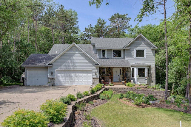 traditional home with a shingled roof, a porch, a front yard, driveway, and an attached garage