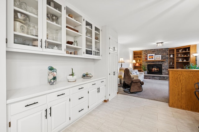 bar featuring built in features, light colored carpet, and a fireplace