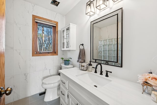 bathroom with tile patterned floors, toilet, tile walls, and vanity