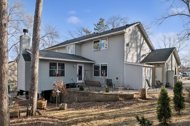 back of house featuring entry steps, a chimney, a patio, and a shingled roof