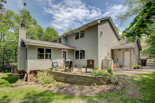 rear view of house featuring a chimney and a patio