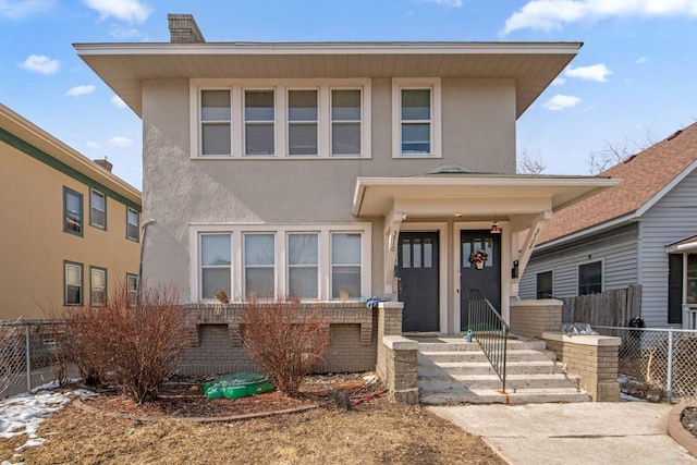 american foursquare style home with brick siding, stucco siding, and fence