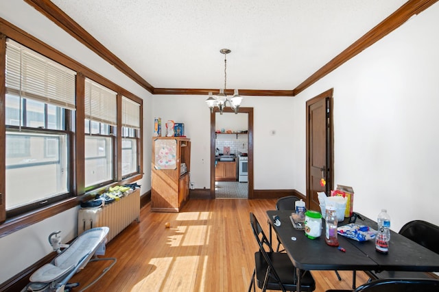 dining space with light wood-style floors, an inviting chandelier, radiator heating unit, and crown molding