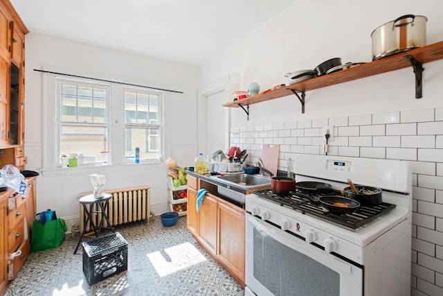 kitchen with radiator, white range with gas cooktop, open shelves, a sink, and backsplash