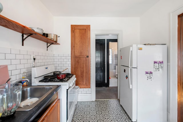 kitchen featuring open shelves, decorative backsplash, brown cabinetry, white appliances, and a sink