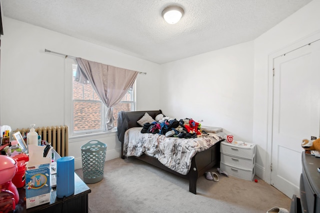 bedroom with radiator, carpet, and a textured ceiling