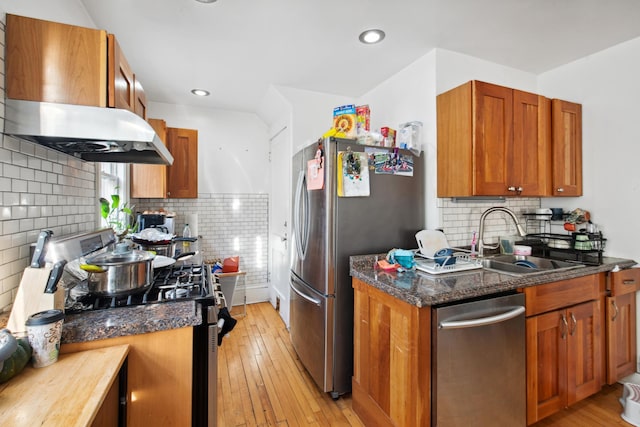 kitchen with light wood-type flooring, a sink, stainless steel appliances, brown cabinetry, and extractor fan