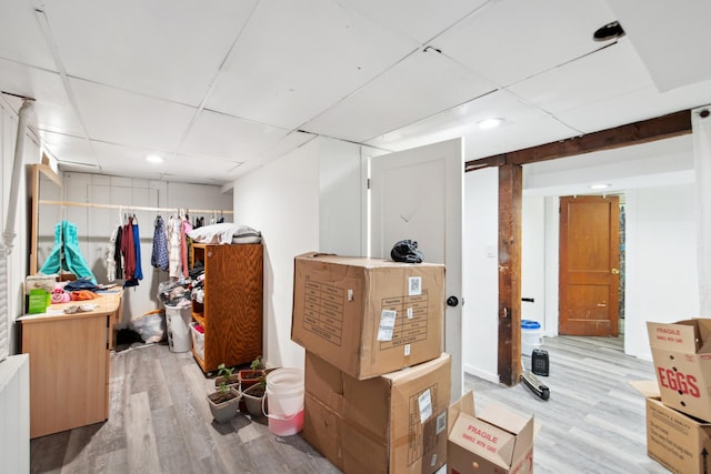 basement with a paneled ceiling and light wood-style flooring