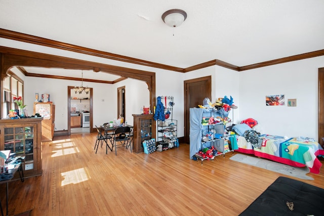 recreation room with a notable chandelier, crown molding, baseboards, and wood-type flooring