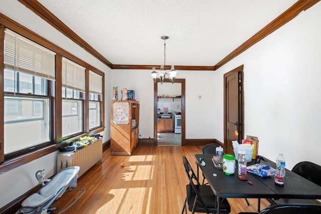 dining space with an inviting chandelier, radiator heating unit, light wood-style flooring, baseboards, and ornamental molding