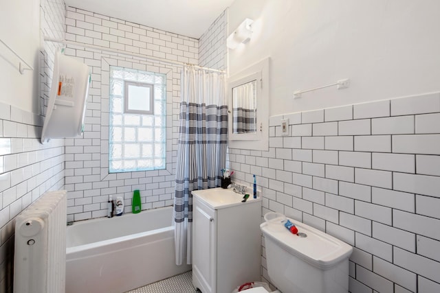 bathroom featuring tile walls, radiator heating unit, toilet, and vanity
