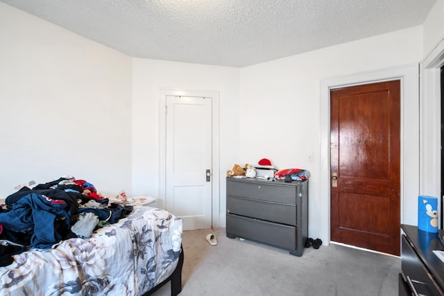 bedroom with a textured ceiling and light colored carpet